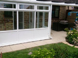 Exterior view to a white uPVC lean to conservatory with base panels